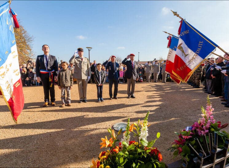 Un groupe composé du maire et de deux enfants, ainsi que d'un militaire et deux anciens combattants saluent lors de la commémoration devant le monument aux morts