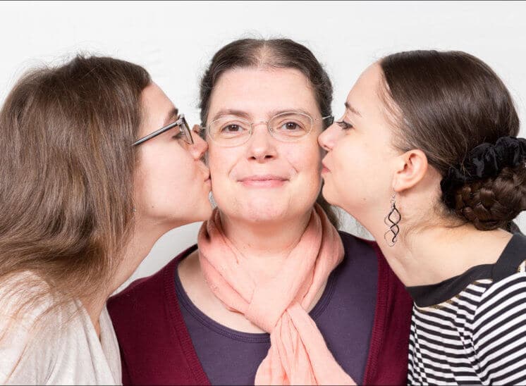Deux filles embrassent leur maman chacune sur une joue, à l'occasion de son anniversaire
