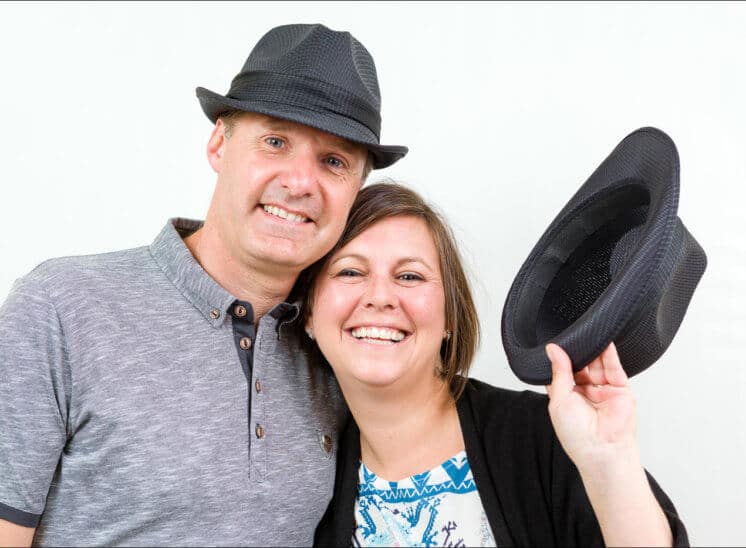 Un couple joue avec des chapeaux. Ils posent naturellement lors d'une séance de shooting photo.