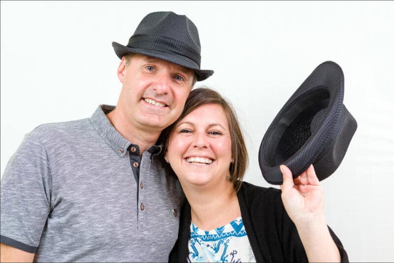 Un couple joue avec des chapeaux. Ils posent naturellement lors d'une séance de shooting photo.