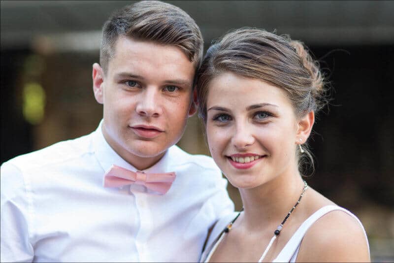Un jeune couple sourit devant l'objectif lors d'une cérémonie familiale