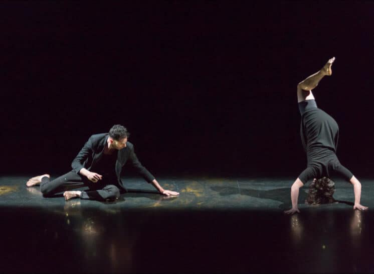 Deux personnes en tenue sombre dancent sur une scène