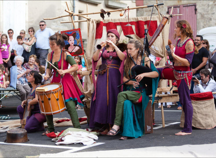 Cinq femmes habillées en style médiéval jouent de différents instruments de musique