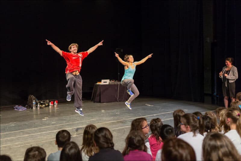 Deux danseurs de hip hop sautent en levant les bras.