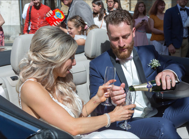 Les mariés boivent une coupe de champagne dans la voiture cabriolet