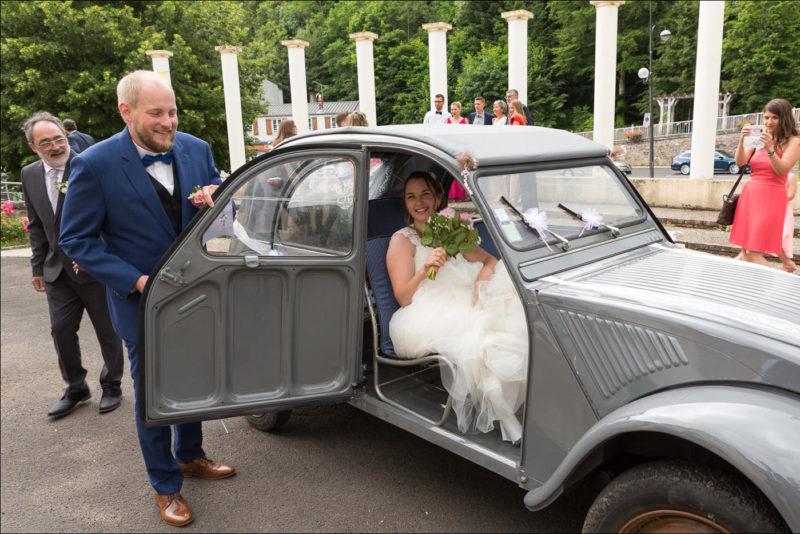 Le marié tient la porte de la 2cv ou se trouve la mariée