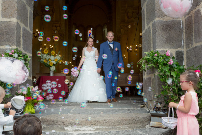 Les enfants font des bulles de savon et les mariès sortent de l'église