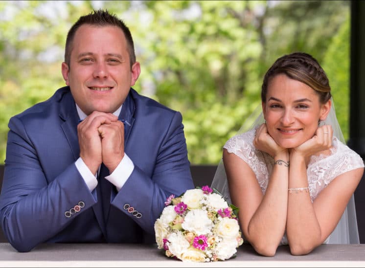 Les mariés posent lors des photos de couple, de chaque côté du bouquet