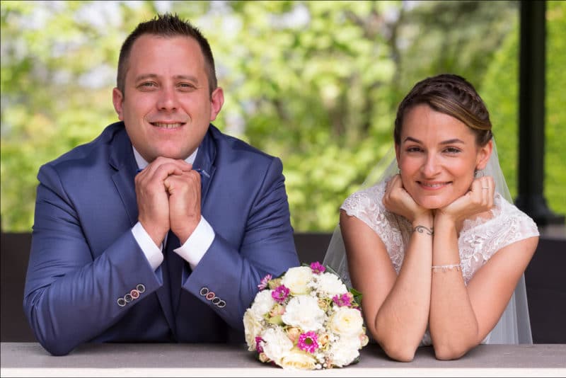 Les mariés posent lors des photos de couple, de chaque côté du bouquet