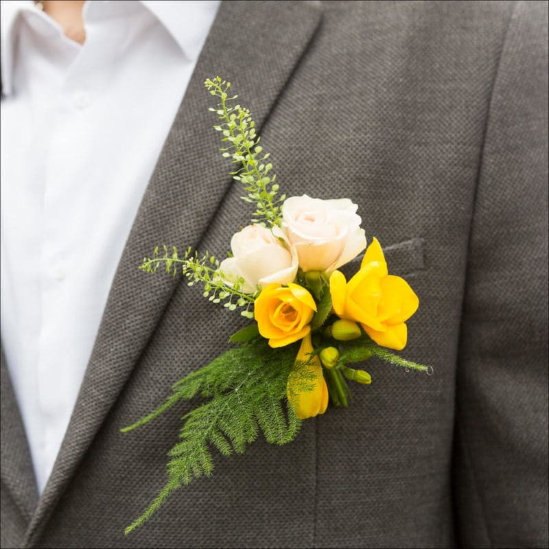 Gros plan sur la boutonnière fleurie du marié