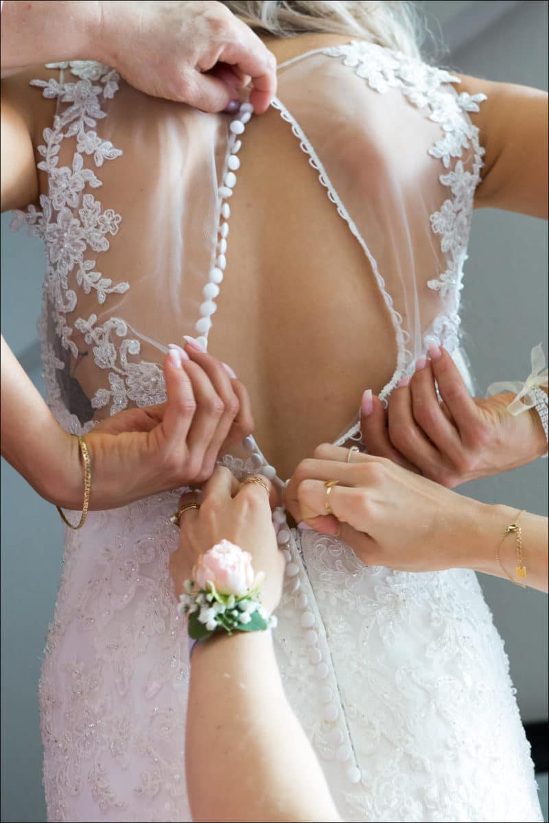 Les fille d'honneur boutonnent la robe de la mariée