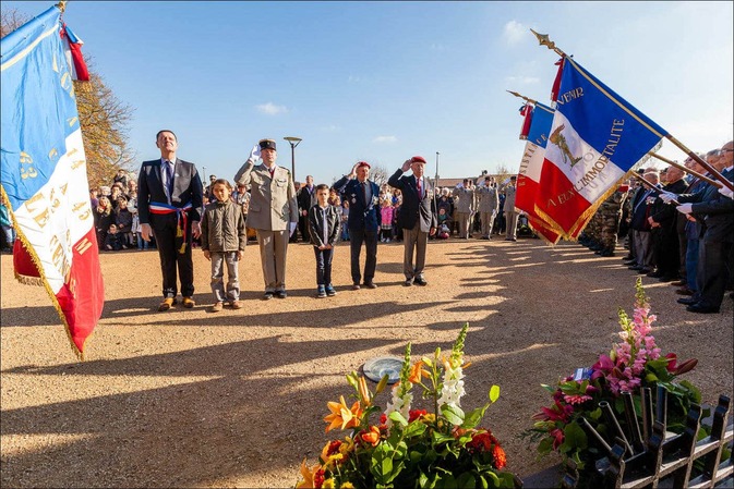 Un groupe composé du maire et de deux enfants, ainsi que d'un militaire et deux anciens combattants saluent lors de la commémoration devant le monument aux morts